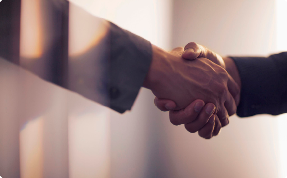 スーツ姿の男性同士の、握手する手にフォーカスしたイメージ。