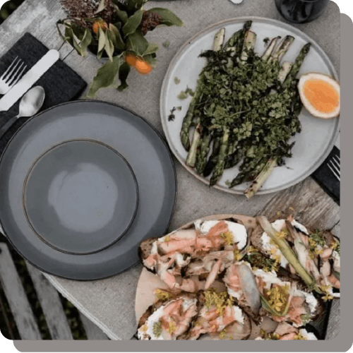 野菜や海鮮を使用した料理が、カトラリーなどと一緒に机に並べられているイメージ