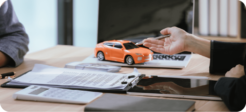 打ち合わせをするイメージ 机上にはミニカー、パソコン、書類などが置かれている