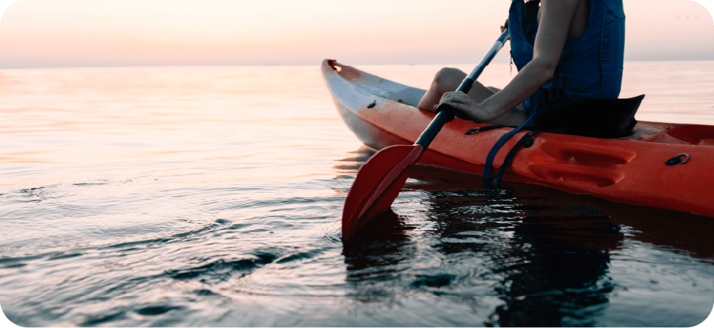 カヌーに乗って夕日の海を渡るイメージ