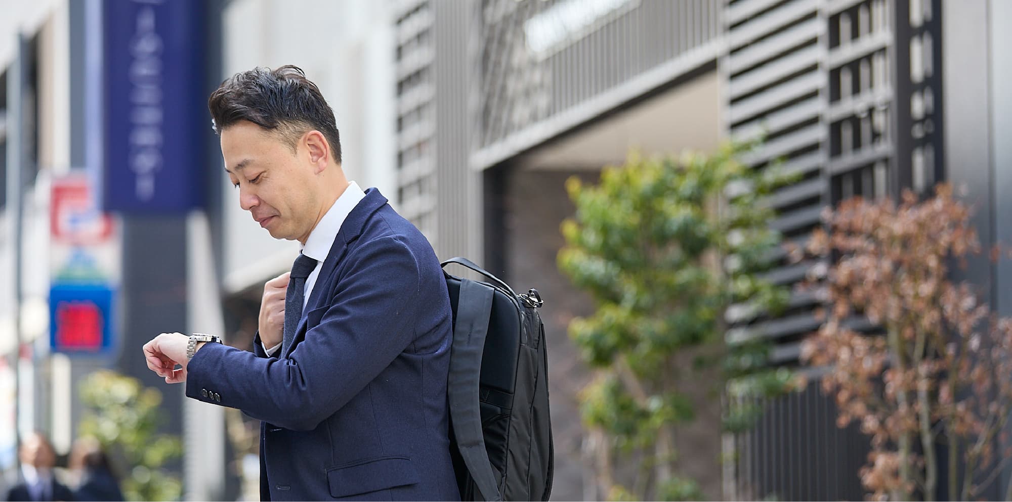 カバンを持ち、腕時計を確認しながら仕事に向かうM.F